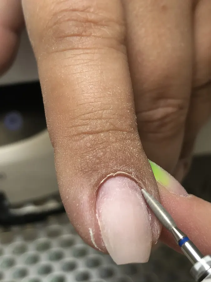 Close-up of precise e-file cuticle work during a dry manicure